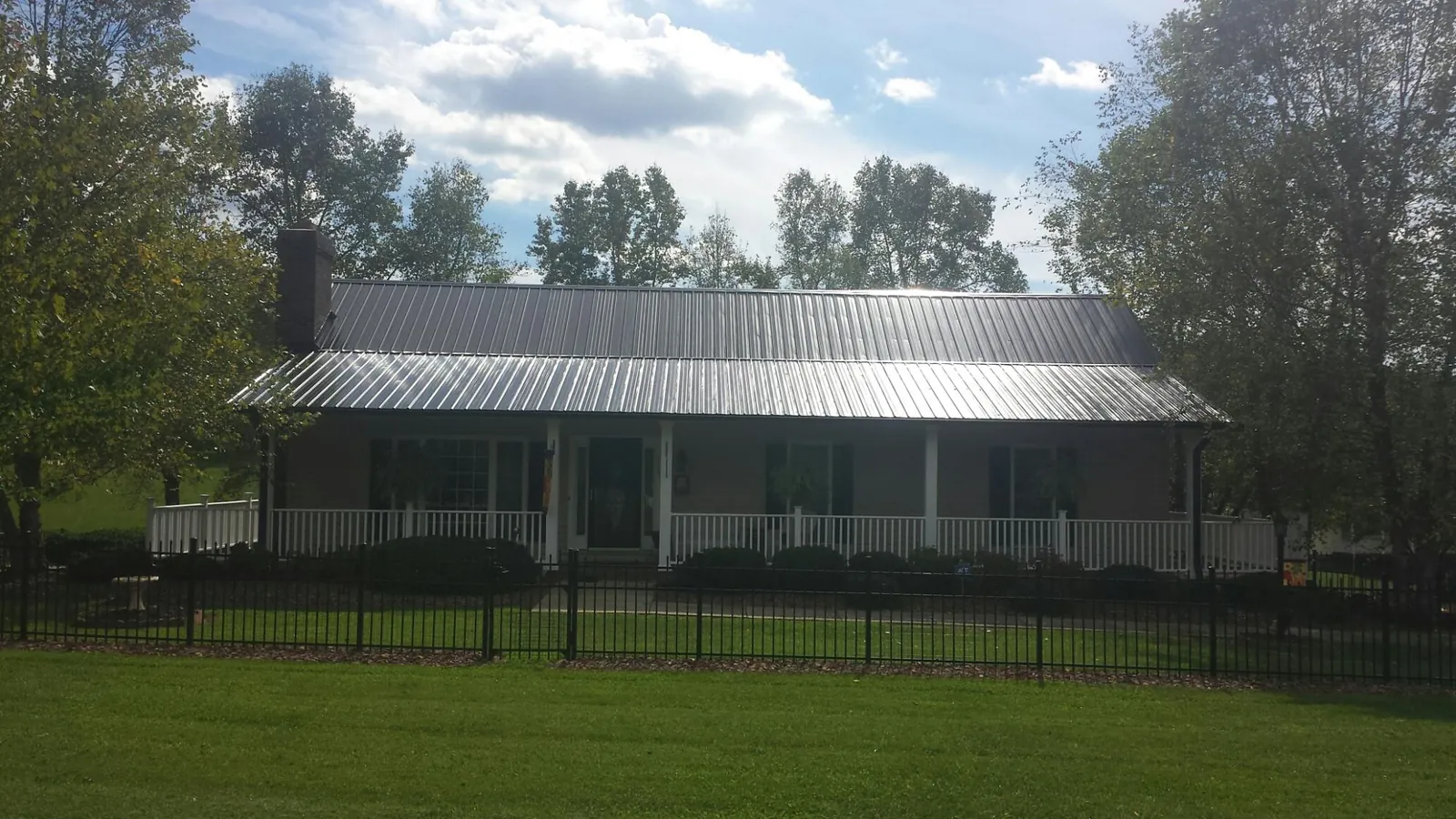 Gray metal roof on a brick ranch with a full width front porch — Gutter Guard Installation work by our crew in Ponca City