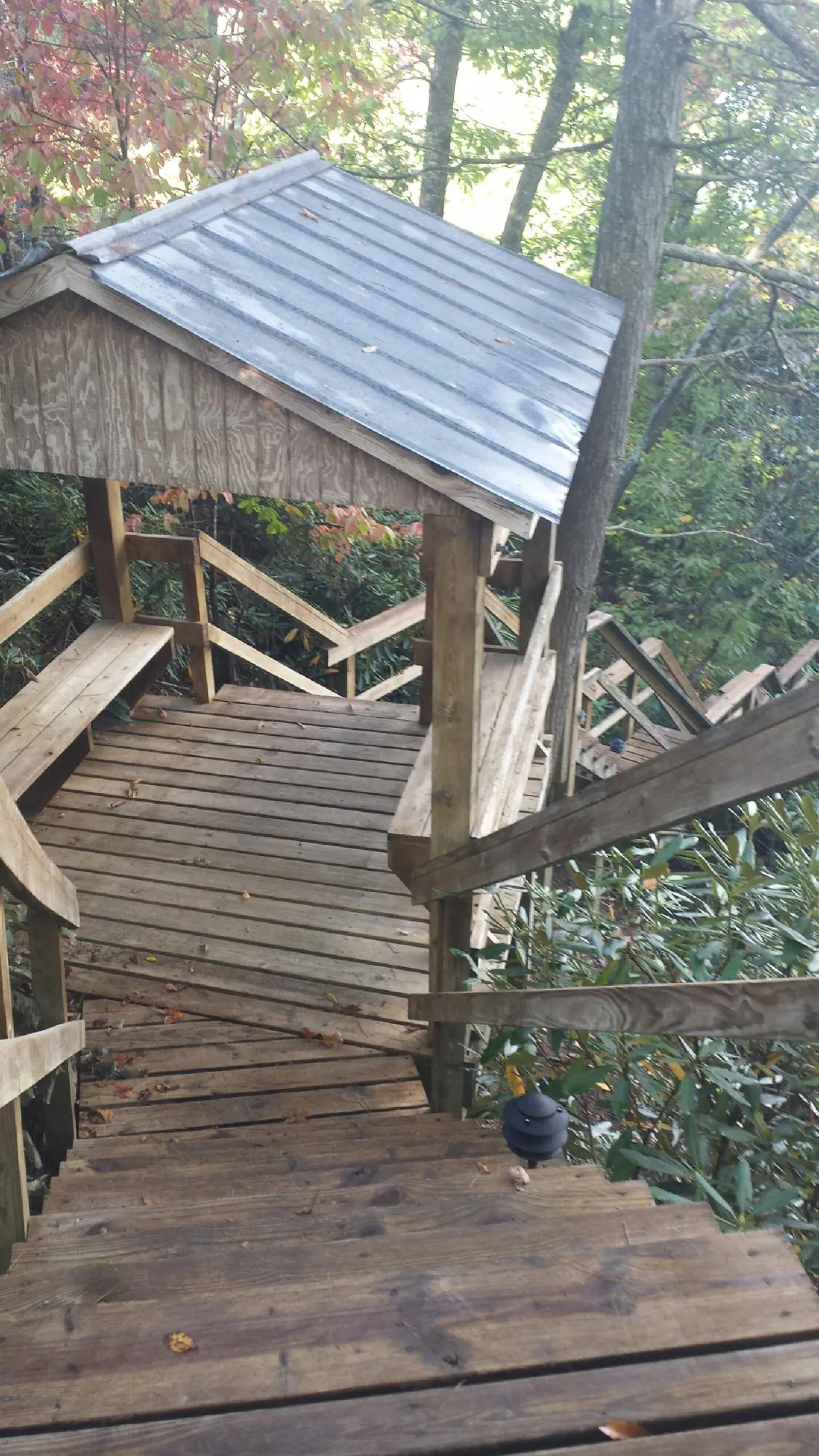 Metal roofed shelter over wooden steps on a wooded walkway — Skylight Repair & Installation work by our crew in Ponca City