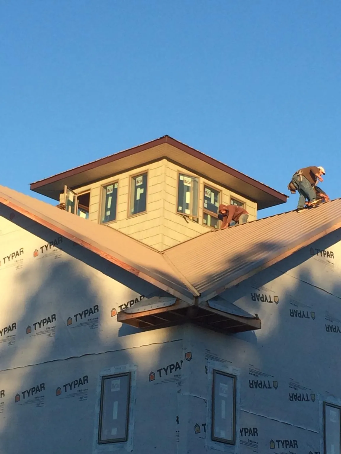 Roofers working around a rooftop cupola on a new metal roof at sunset — Roof Waterproofing in Ponca City by Roofing Brothers